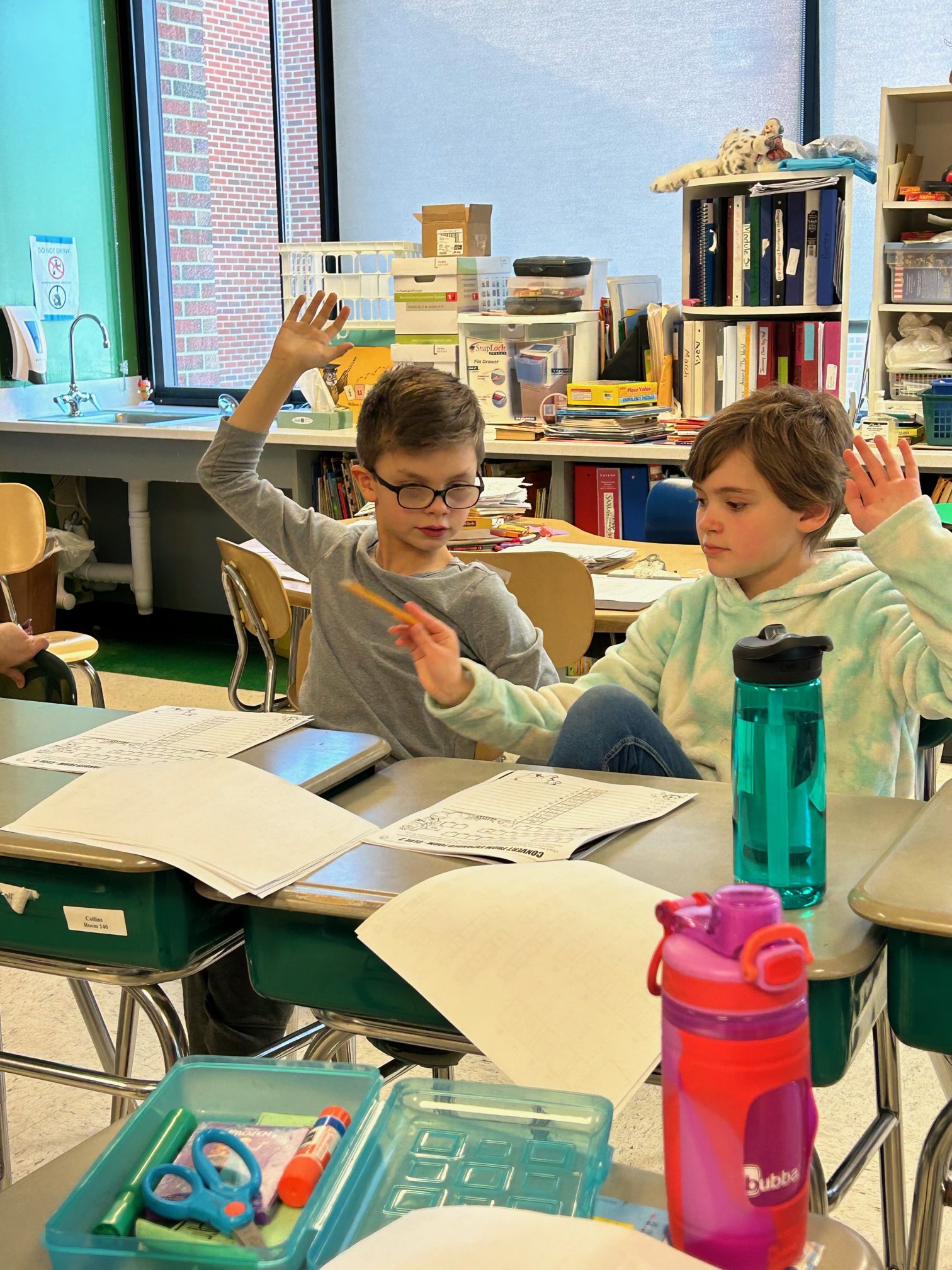 Two boys raise their hands to answer a question.