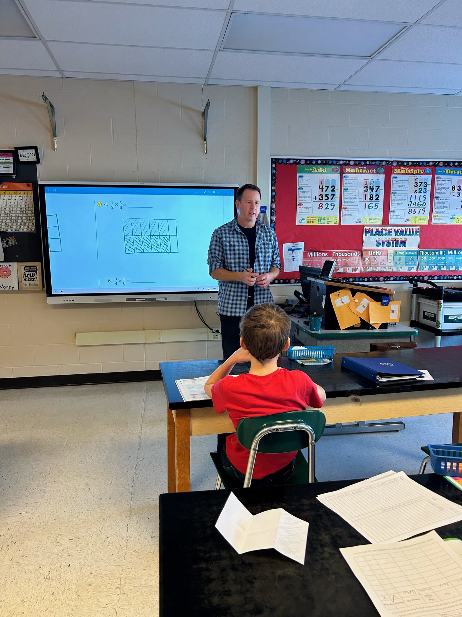 Math teacher stands in front of electronic board.