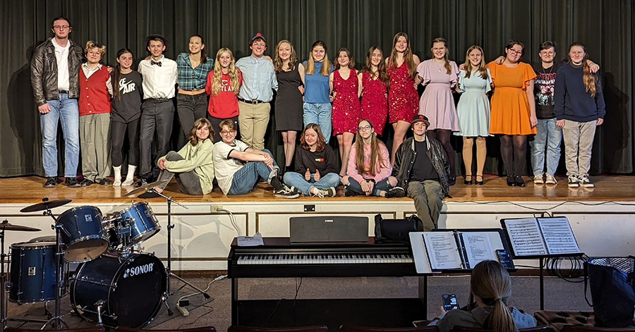 Cast of "Little Shop of Horrors" embracing on stage.