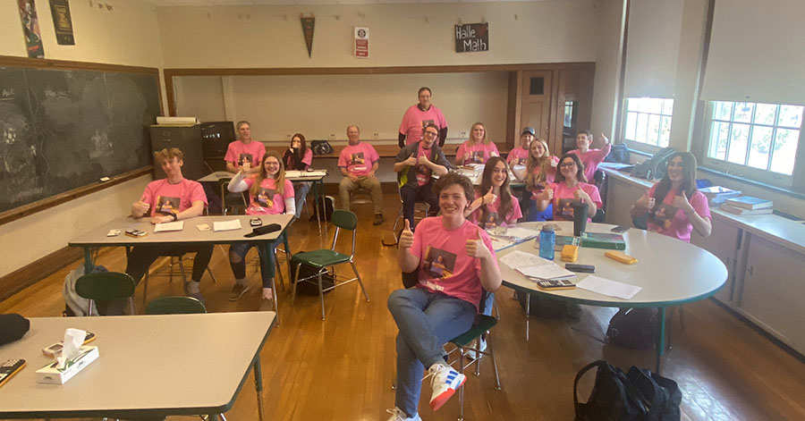 Group of students wearing matching shirts give the thumbs-up.