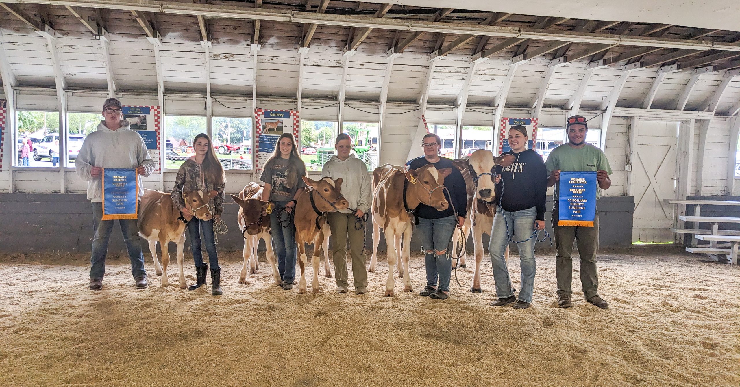 FF students stand with cows in bard holding Premier Exhibitor Award
