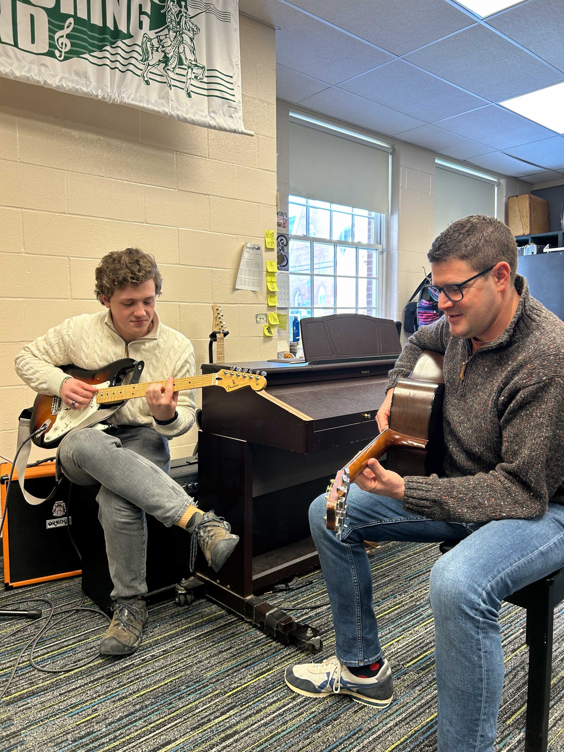 Principal plays guitar alongside student.