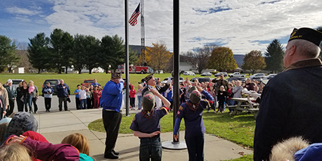 students and veterans salute the american flag during a flag raising ceremony