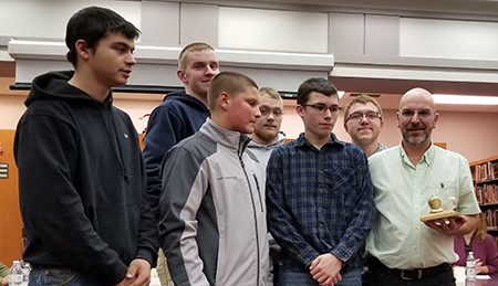 scott gray poses with students and his golden knight award