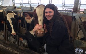 a student poses for a picture with a cow