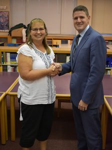 board of education president pamela standhart and matt sloane shake hands