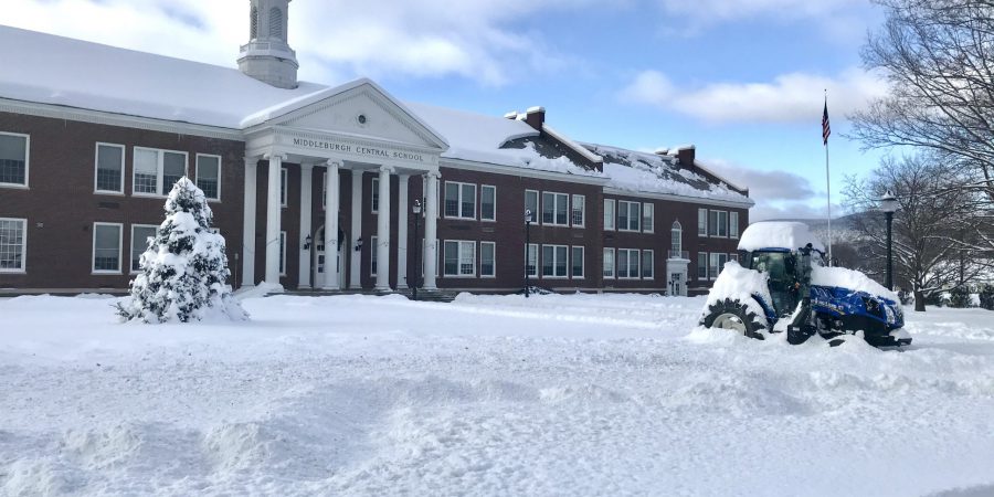 High school courtyard covered in snow with holiday tree and decorated tractor