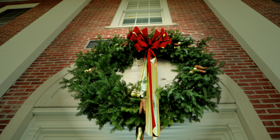 Holiday wreath above high school doors with red and gold ribbon