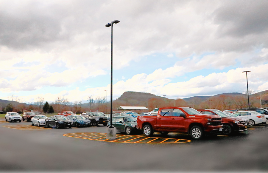 Parking lot filled with cars and trucks, light posts, on a cloudy day