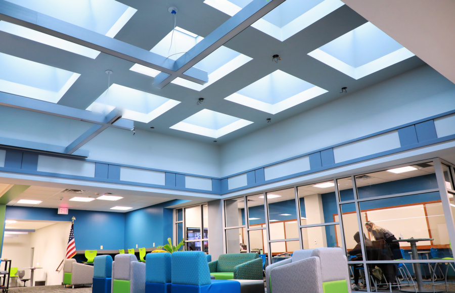 skylighting under colorful chairs with a glass encased classroom to the side