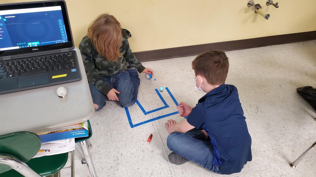 two students made a tape maze on the floor and are trying to get their robot to follow it