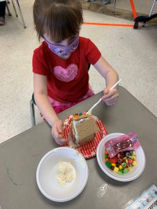 student spreads icing on gingerbread house