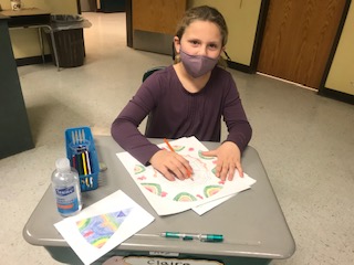 3rd grade art student drawing and coloring a Tibetan Mandala is just starting to color around the outside of her patterns