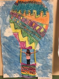 drawing of blue, yellow, orange, green, yellow and magenta jagged and circular patterns on hot air baloon up in the sky with a picture of student in the basket of the baloon