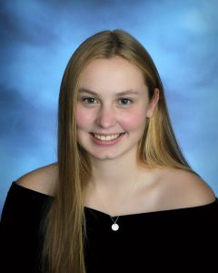senior picture of girl with blonde hair wearing a black drape and smiling big with rosy cheeks