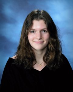 senior picture of a girl with dark long hair smiling without showing her teeth