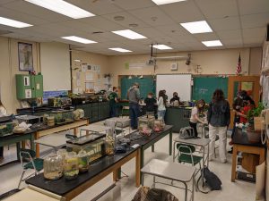 in a science classroom, two teachers and eight students work on teting water