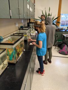 two students test water with their teacher watching