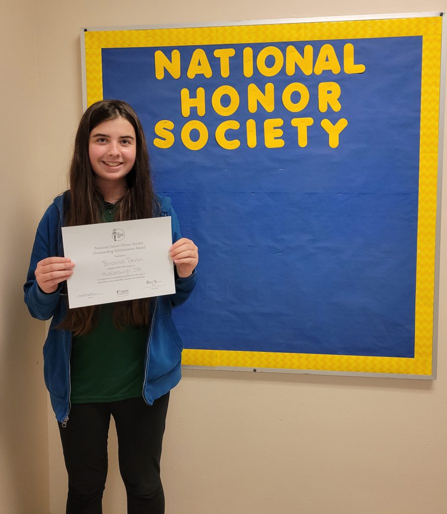 student with dark hair and a big smile holds certificate up with both hands 