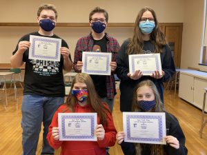 three students standing holding certificates and two kneeling holding certificates