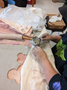 close up of hand molding clay into a poppy