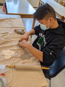 student is working with clay to make poppies at a table