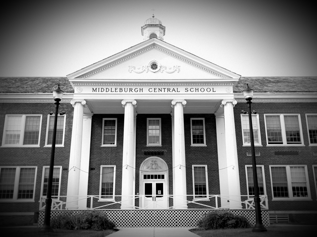 black and white dramatic shot of bricj highschool with four white pillars