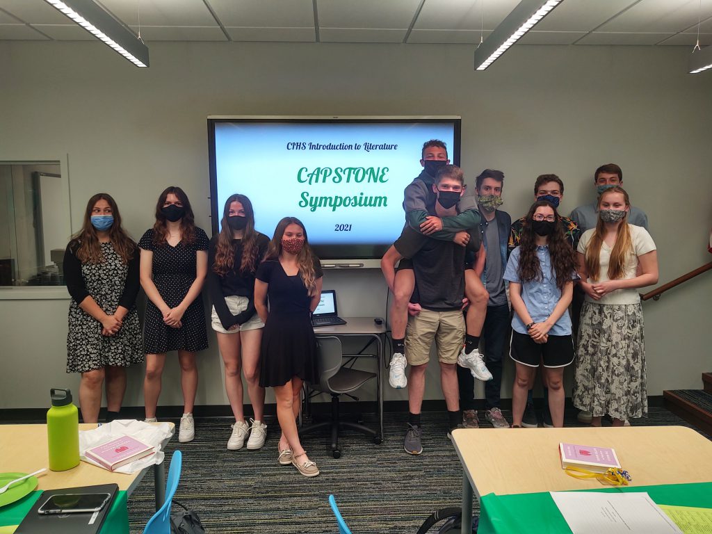 students standing around a sign that says capstone symposium