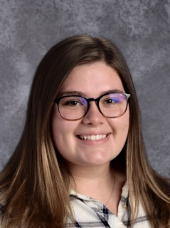 student with brown hair and glasses smiling