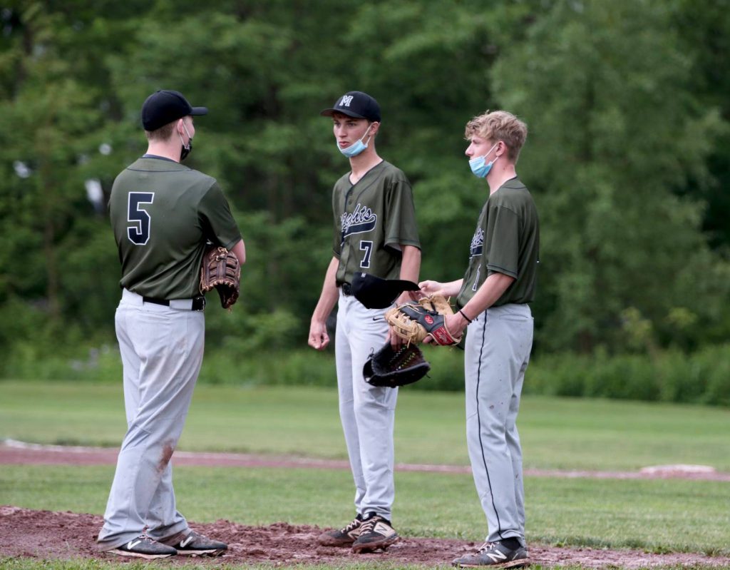 three baseball players on the field talking