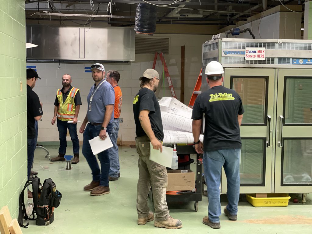 construction workers in school kitchen looking at plans 