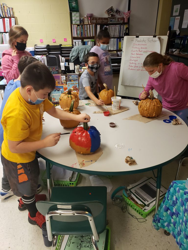 young students decorate pumpkins 