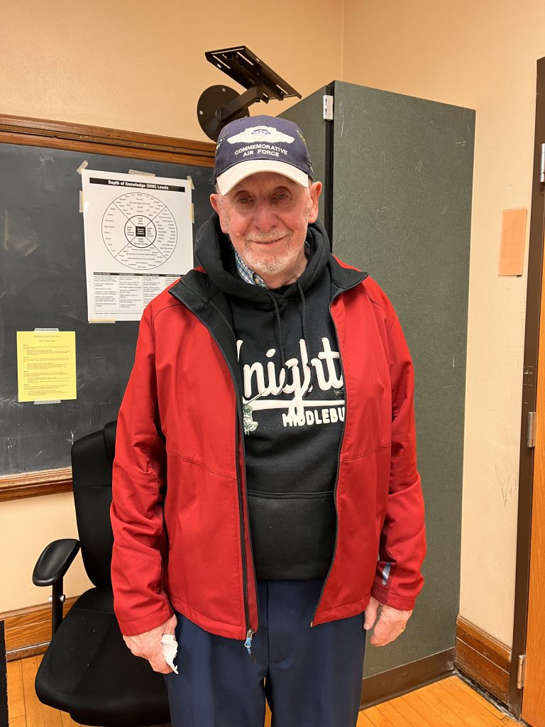 Army Veteran wearing a red jacket and a blue baseball hat