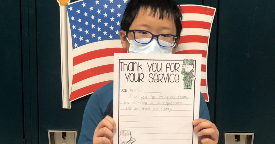 student holds up letter he wrote to a veteran
