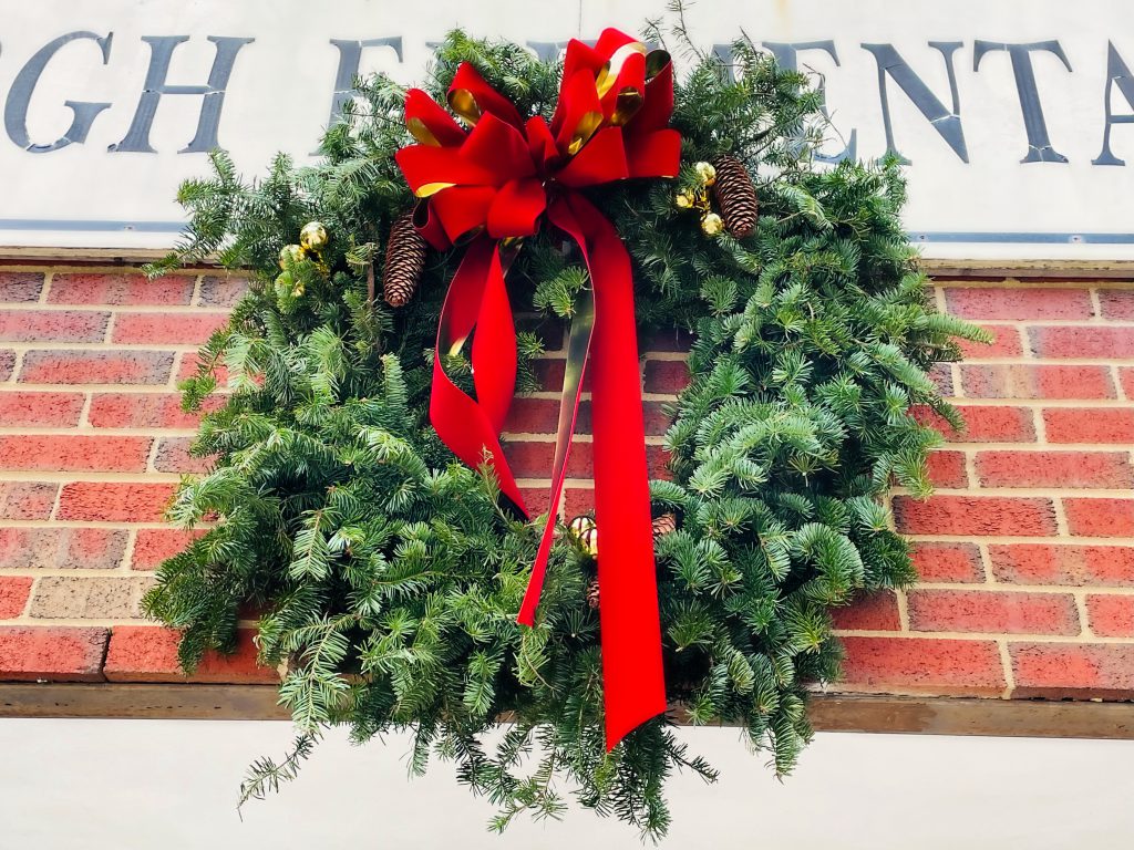 looking up at green pine wreath with a big red bow