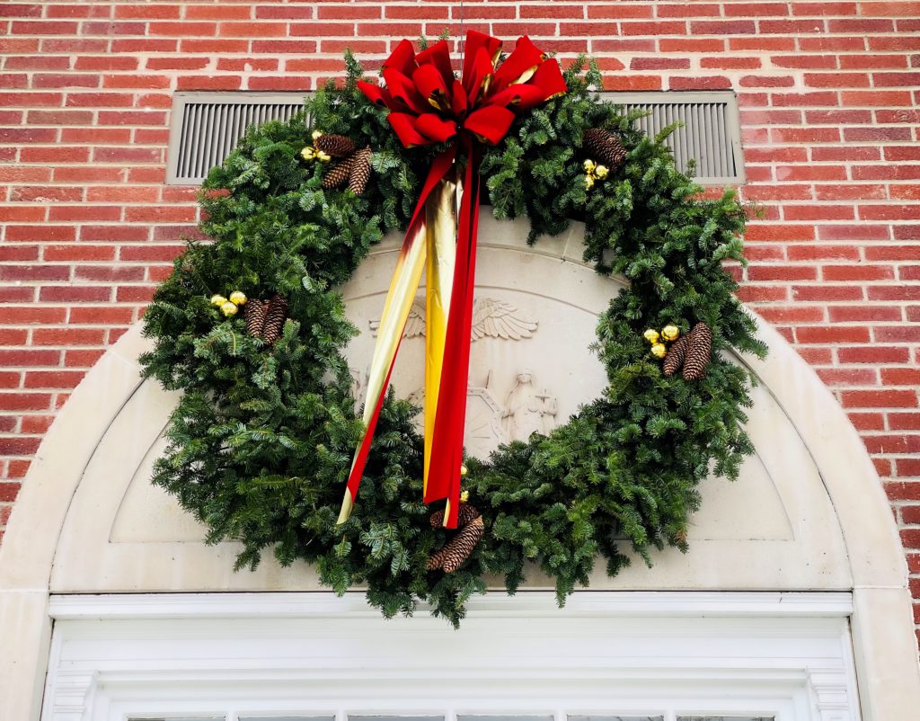 pine holiday wreath with a red and gold bow, gold accents and pine cones