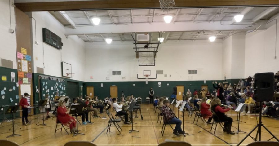 students sitting in rows in gym playing instruments