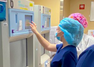 students wearing medical scrubs and head cap pushes button on screen