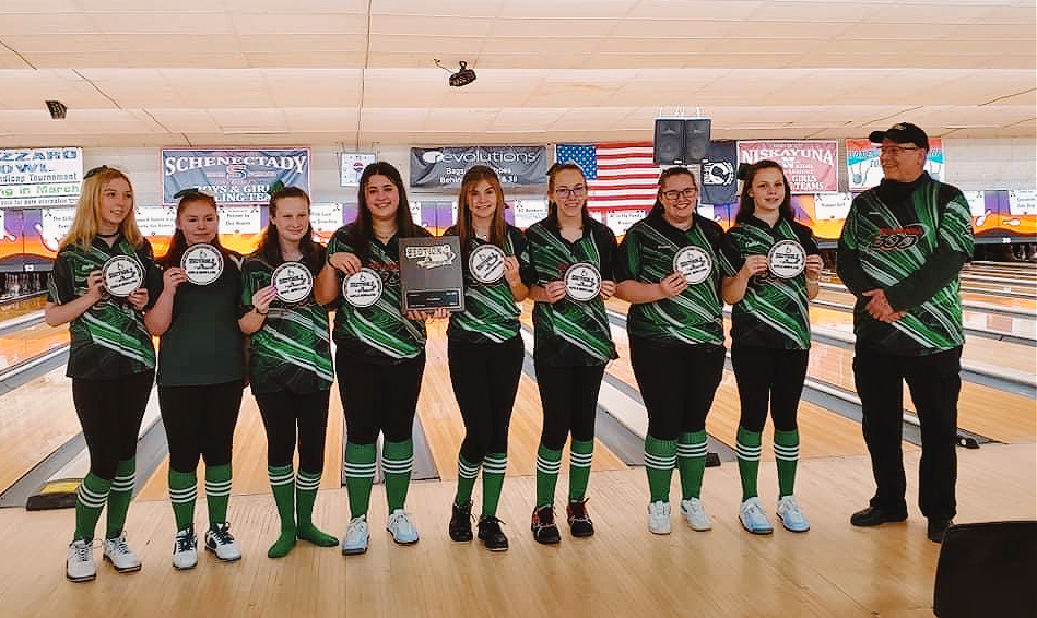 eight bowlers hold up their awards and their coach looks at them proudly