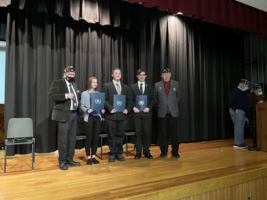 three students holding awards with two American Legion members on each side of them