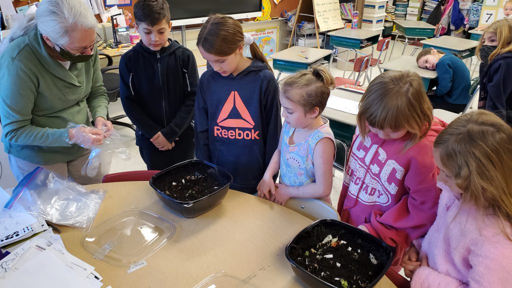 students standing around containers with compost