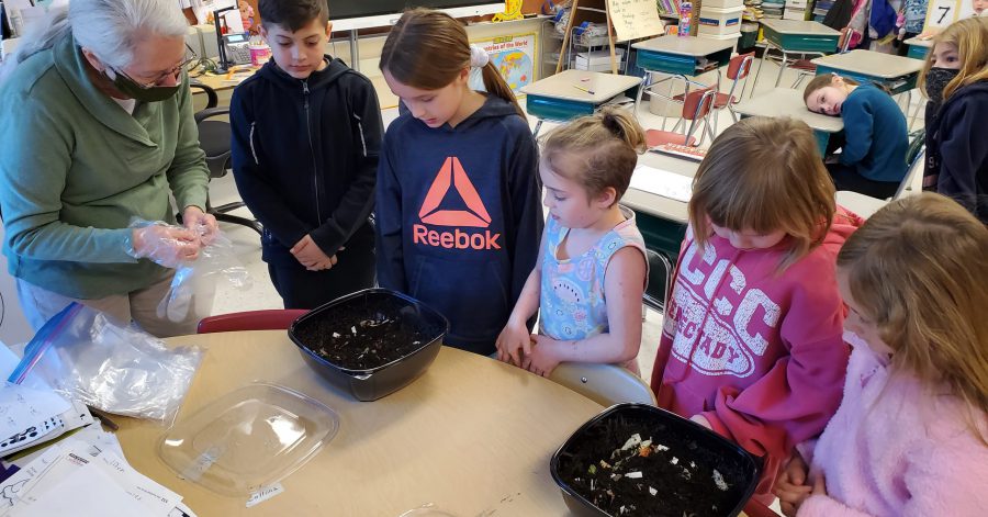 students standing around containers with compost