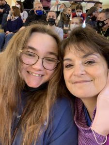 girl with long sandy hair and glasses smiles really big with woman with brown hair who is also smiling