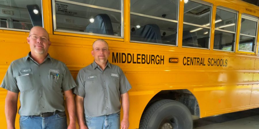two mechanics standing in front of a bus
