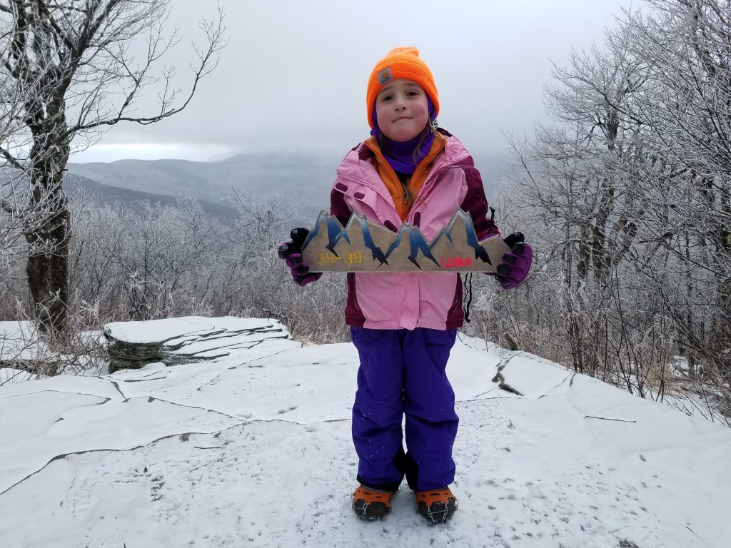 4 year old stands on top of snowy mountain