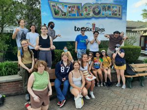 a group of students smiling and making funny faces in front of a six flags sign