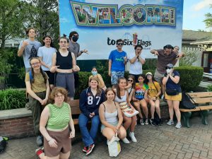 a group of students smiling and making funny faces in front of a six flags sign