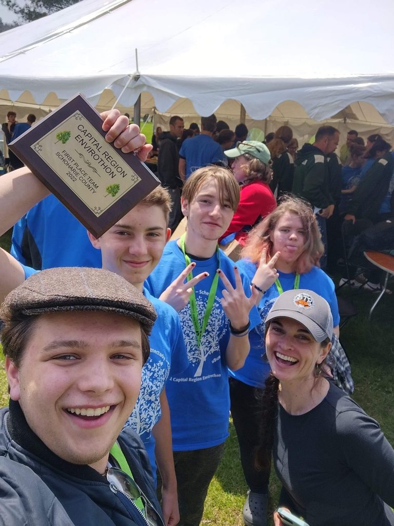 four students and a teacher take a selfie with their first place plaque