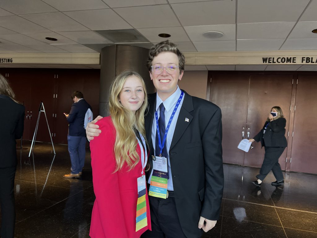 two students dressed in business attire get close and smile