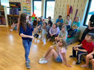 student stands in front of classmates showing her clarinet